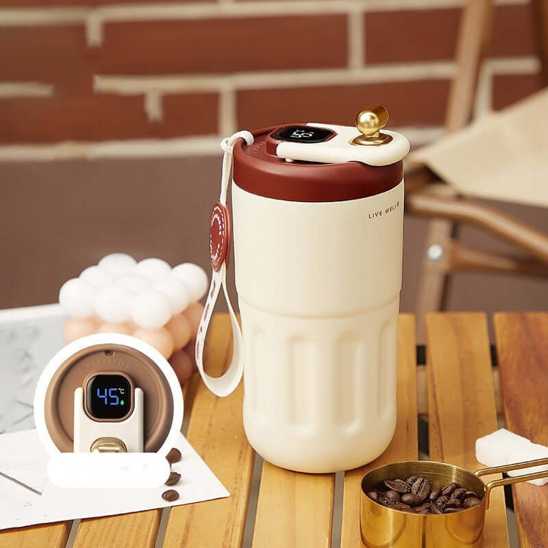 Smart stainless steel travel mug with digital temperature display on a wooden table.
