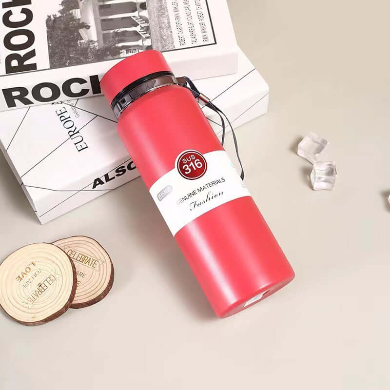 Stainless Steel Vacuum Insulation Cup in pink next to books and coasters, showcasing its stylish design and smart technology.